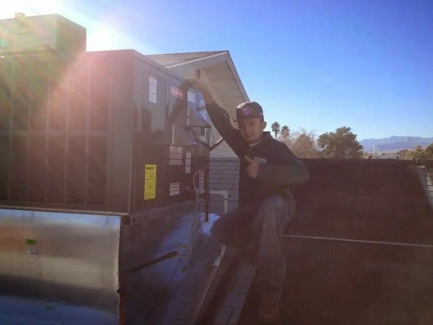HVAC technician performing Air Duct Cleaning on a rooftop unit in Forestdale