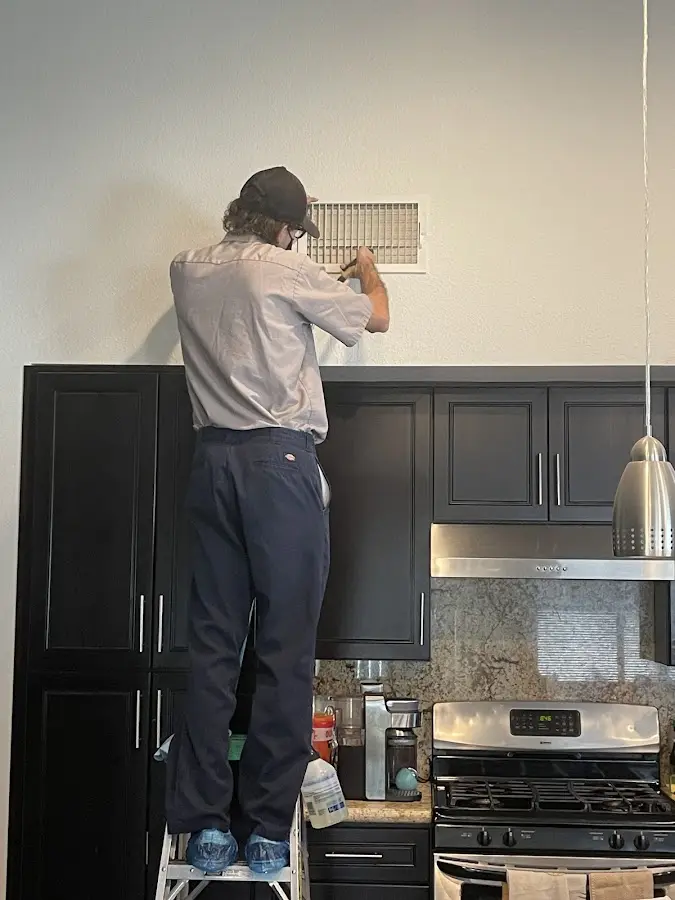Technician inspecting an air vent during HVAC service in Forestdale